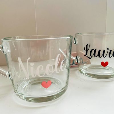 Two clear glass mugs, one with “Nicole” in white and one with “Lauren” in black, each with a small heart