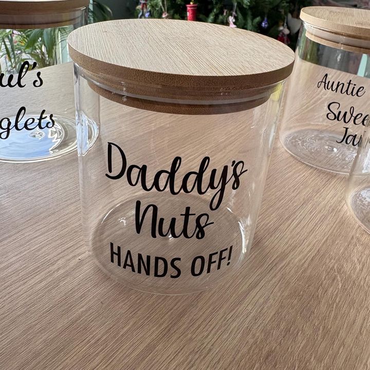 Glass jar with a bamboo lid lettered “Daddy’s Nuts, hands off!” in black vinyl